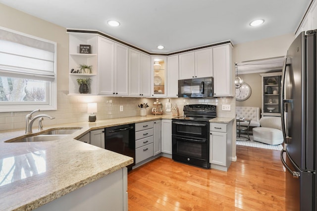 kitchen featuring sink, black appliances, light hardwood / wood-style floors, white cabinets, and light stone countertops