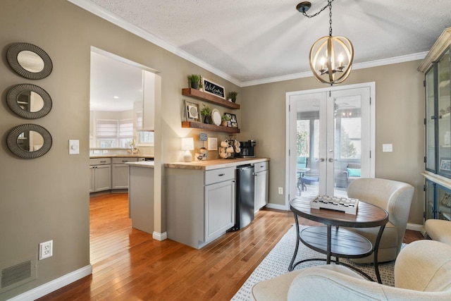 bar featuring refrigerator, hanging light fixtures, light hardwood / wood-style floors, plenty of natural light, and french doors