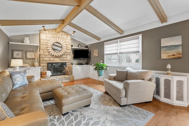 living room featuring vaulted ceiling with beams, a fireplace, and light wood-type flooring