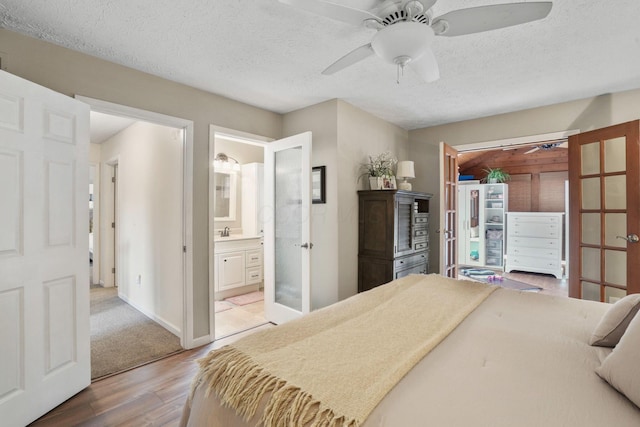 bedroom featuring sink, ensuite bath, hardwood / wood-style floors, and a textured ceiling