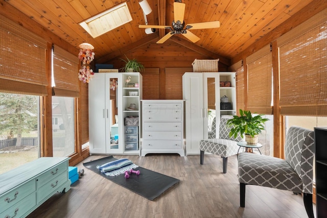 living area featuring dark hardwood / wood-style flooring, lofted ceiling with skylight, wooden ceiling, and wood walls