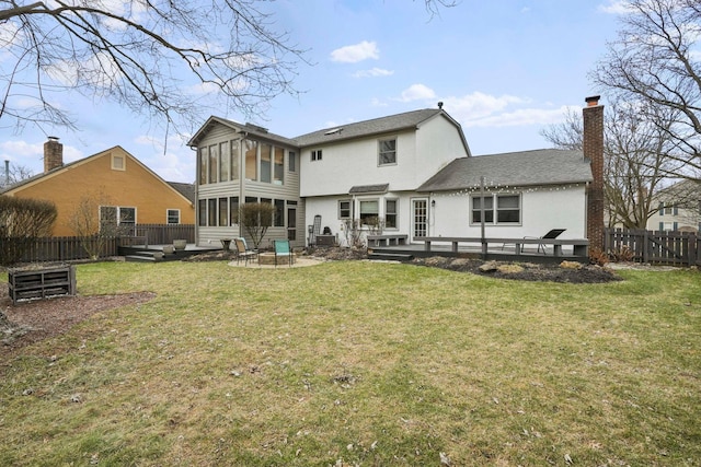 back of property featuring a deck, a yard, an outdoor fire pit, a patio area, and a sunroom