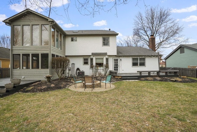 rear view of property featuring a patio, a sunroom, a lawn, and a fire pit