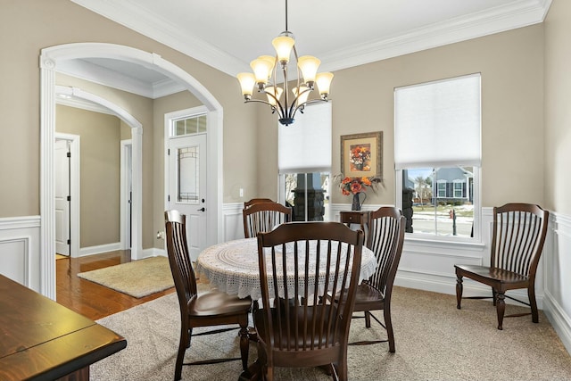 dining space with crown molding, wood-type flooring, and an inviting chandelier