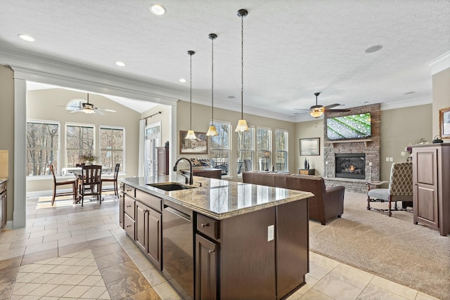 kitchen with sink, crown molding, decorative light fixtures, a center island with sink, and dishwasher