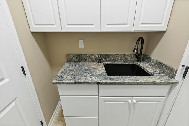 kitchen with sink, dark stone counters, and white cabinets