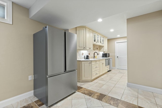 kitchen featuring appliances with stainless steel finishes, sink, backsplash, and cream cabinets