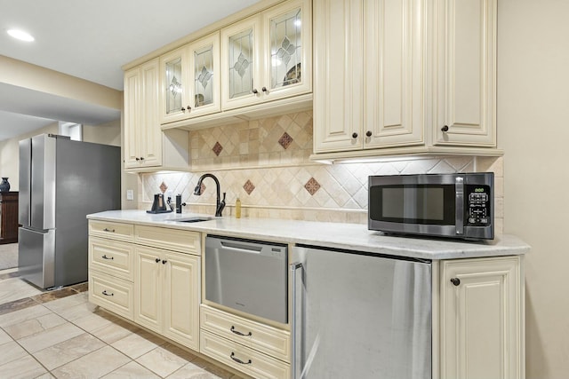 kitchen featuring sink, backsplash, cream cabinets, and stainless steel appliances