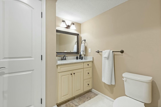 bathroom with vanity, toilet, and a textured ceiling