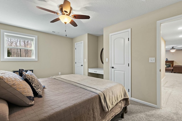 bedroom featuring ceiling fan, light carpet, and a textured ceiling