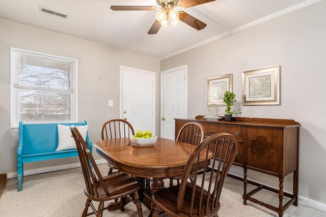 dining area featuring light carpet, ornamental molding, and ceiling fan