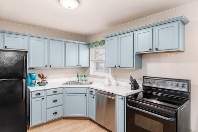 kitchen with sink, range with electric stovetop, black refrigerator, dishwasher, and light hardwood / wood-style floors