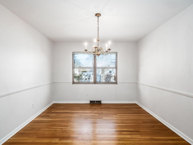 unfurnished room with hardwood / wood-style floors and a notable chandelier