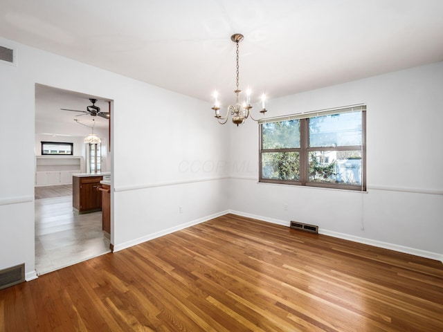 spare room featuring hardwood / wood-style flooring and ceiling fan with notable chandelier