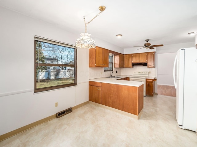 kitchen featuring sink, backsplash, hanging light fixtures, kitchen peninsula, and white appliances