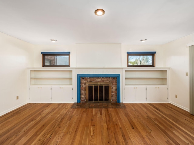 unfurnished living room with a brick fireplace and hardwood / wood-style floors