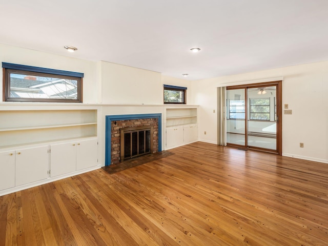 unfurnished living room featuring wood-type flooring, a healthy amount of sunlight, and a fireplace