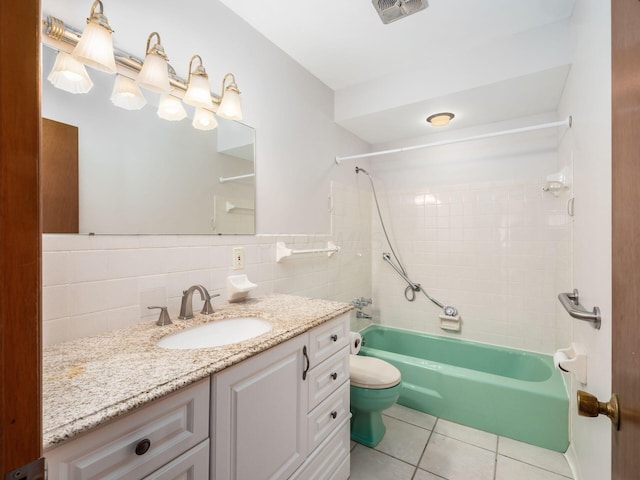 full bathroom with tile patterned floors, toilet, tile walls, vanity, and tiled shower / bath combo