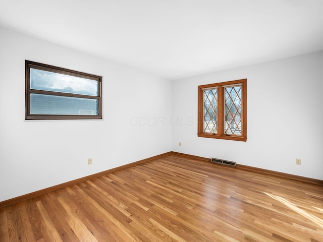 empty room with a wealth of natural light and light hardwood / wood-style flooring