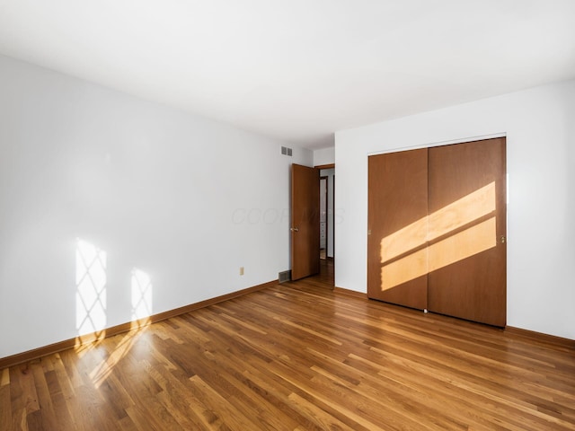 unfurnished bedroom with wood-type flooring and a closet