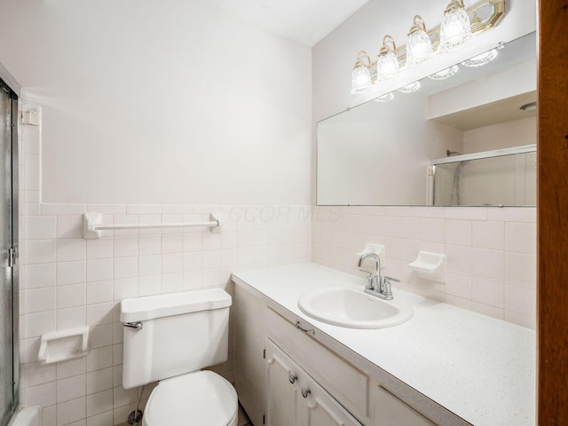 bathroom featuring vanity, toilet, an enclosed shower, and tile walls