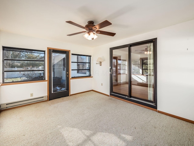 carpeted empty room featuring ceiling fan and a baseboard heating unit