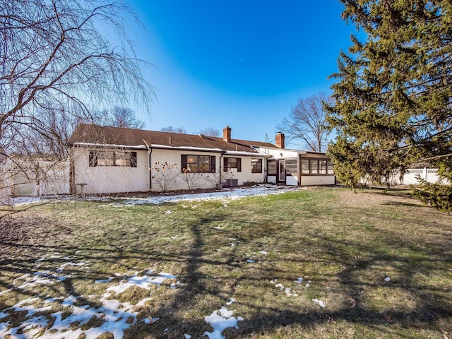 snow covered house with a sunroom and a yard