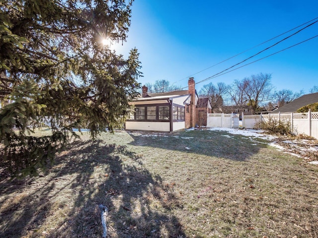 rear view of house with a sunroom and a lawn