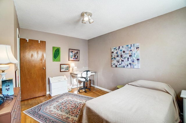 bedroom with a textured ceiling and light hardwood / wood-style floors