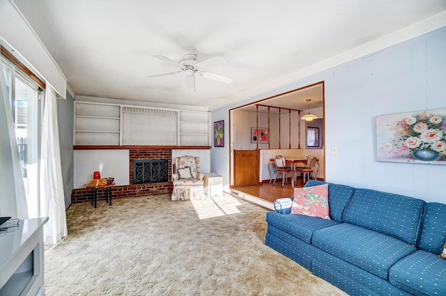 carpeted living room with a brick fireplace and ceiling fan