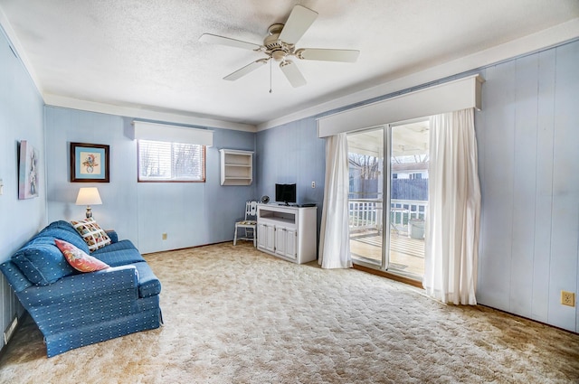 living area with light carpet, a textured ceiling, and ceiling fan