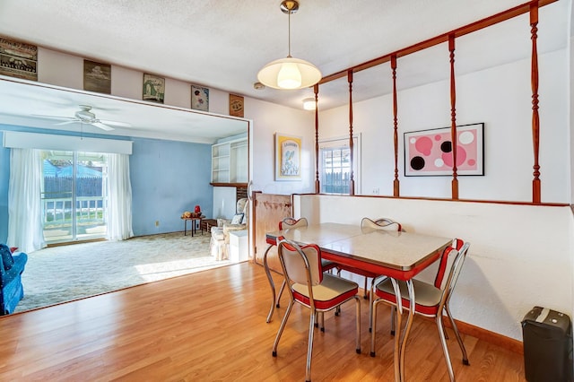 dining space with ceiling fan, a healthy amount of sunlight, wood-type flooring, and a textured ceiling