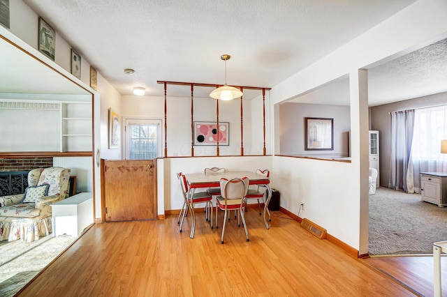 dining space featuring plenty of natural light, a textured ceiling, and light hardwood / wood-style floors