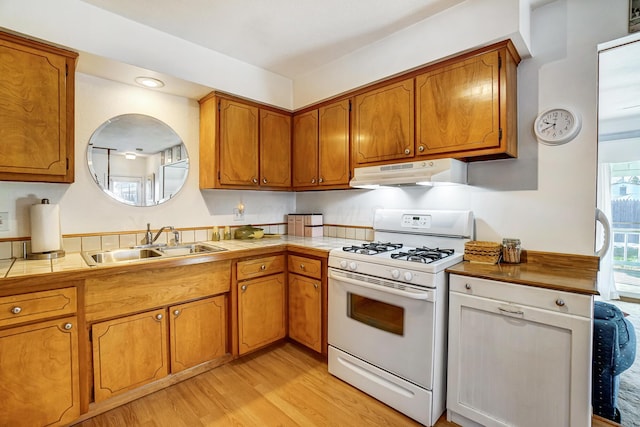 kitchen with sink, tile countertops, white range with gas stovetop, and light wood-type flooring