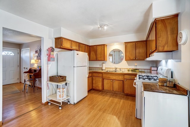 kitchen featuring sink, white appliances, and light hardwood / wood-style flooring