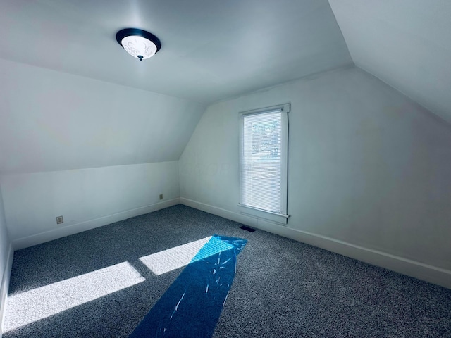 additional living space featuring vaulted ceiling and dark carpet