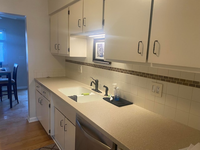 kitchen with tasteful backsplash, sink, white cabinets, dark hardwood / wood-style flooring, and stainless steel dishwasher