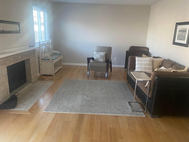 living area with a tiled fireplace and light hardwood / wood-style floors