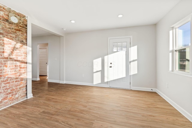 spare room featuring baseboards, brick wall, recessed lighting, and light wood-style floors