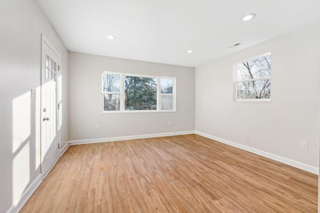 spare room featuring light wood-style floors, plenty of natural light, and baseboards