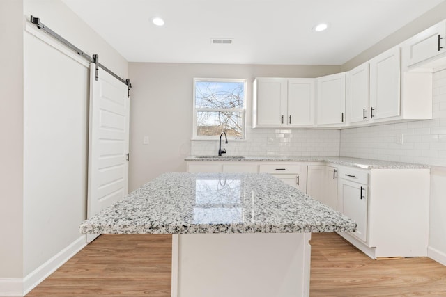 kitchen featuring light stone countertops, a sink, light wood finished floors, and a barn door