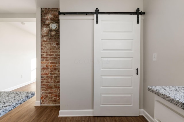 interior details featuring a barn door, baseboards, and wood finished floors