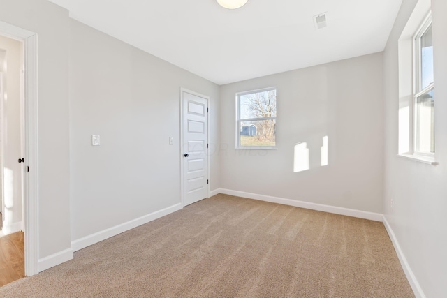 spare room featuring carpet floors, visible vents, and baseboards