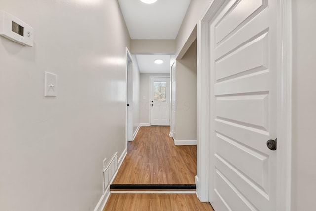 hallway featuring wood finished floors, visible vents, and baseboards