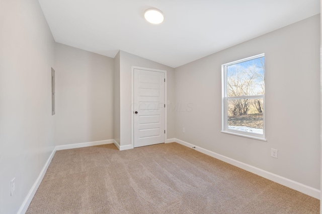 unfurnished room with lofted ceiling, light carpet, and baseboards