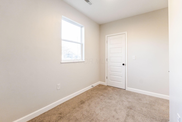 empty room featuring baseboards, visible vents, and light colored carpet