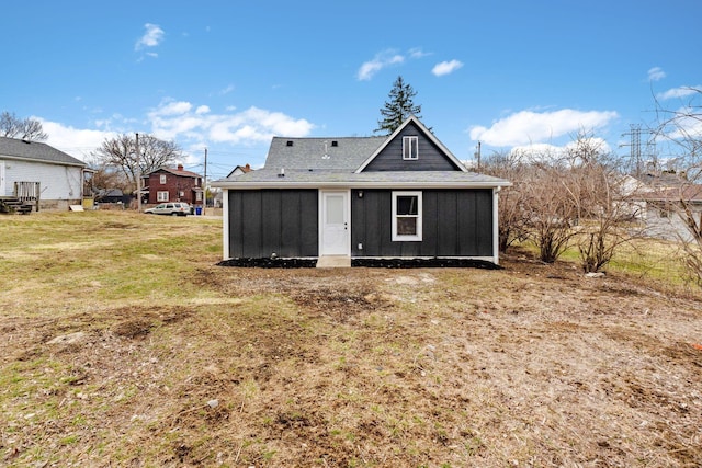 rear view of house with board and batten siding and a yard