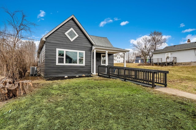 bungalow-style house featuring a front lawn, roof with shingles, a porch, and central air condition unit