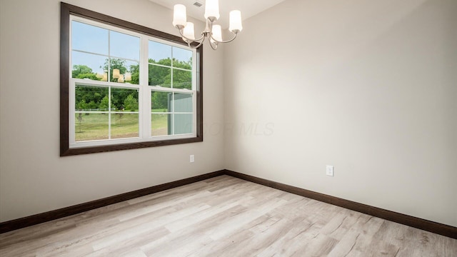 unfurnished room featuring an inviting chandelier and light hardwood / wood-style floors