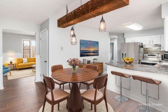 dining space with beamed ceiling and dark hardwood / wood-style flooring